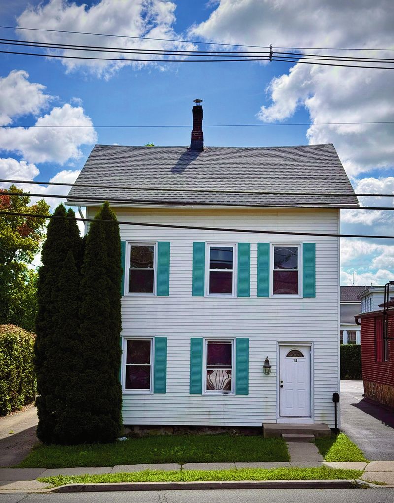 White colonial home with teal shutters