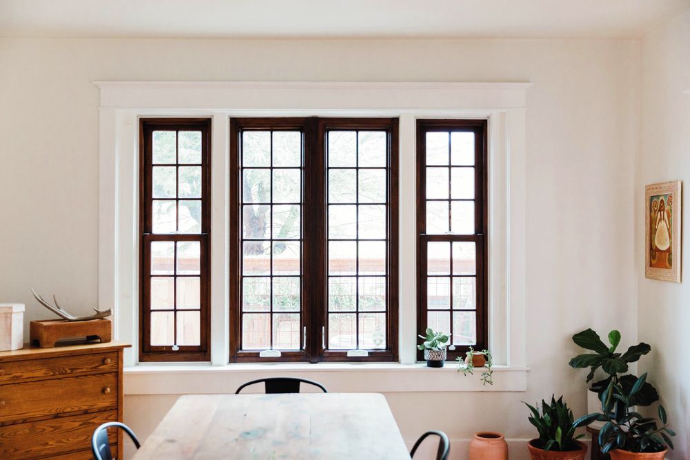 Sunlit dining room with tall windows and plants